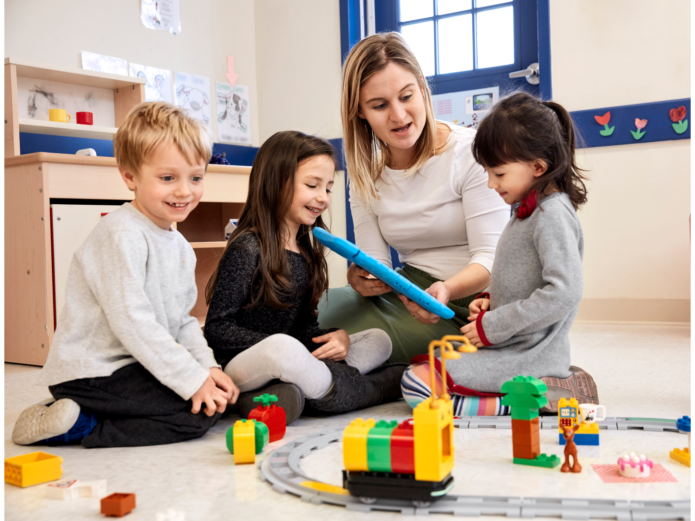 Three preschool children and a teacher playing and coding with Coding Express by LEGO Education